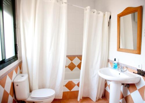 a bathroom with a white shower curtain and a toilet and sink at Caserío de Vazquez 3 in Castilblanco de los Arroyos