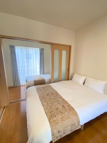 a bedroom with a large white bed and a window at AJITO Hostel 別館 in Shingū