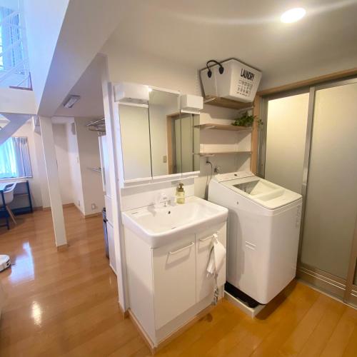a white bathroom with a sink and a mirror at AJITO Hostel 別館 in Shingū