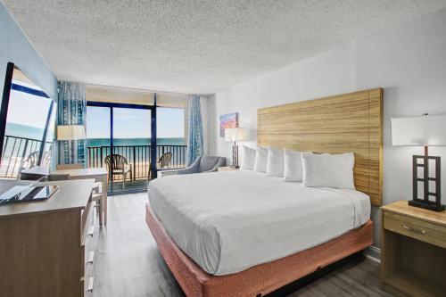 a hotel room with a bed and a desk and a balcony at Ocean Park Resort in Myrtle Beach