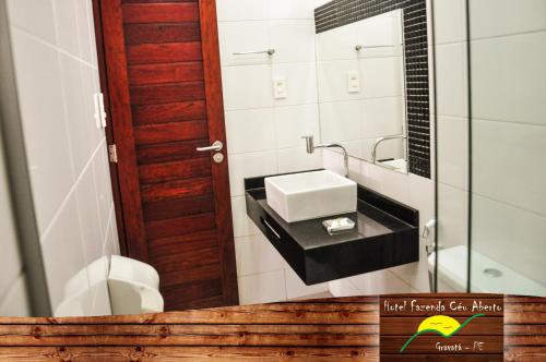 a bathroom with a sink and a toilet and a mirror at Hotel Fazenda Ceu Aberto in Gravatá