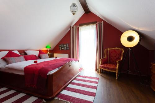 a bedroom with red walls and a bed and a chair at VILLA CANTARE in Obernburg am Main