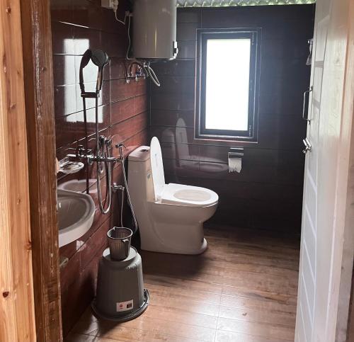 a bathroom with a toilet and a sink and a window at Tamu Kyi Retreat in Kaluk