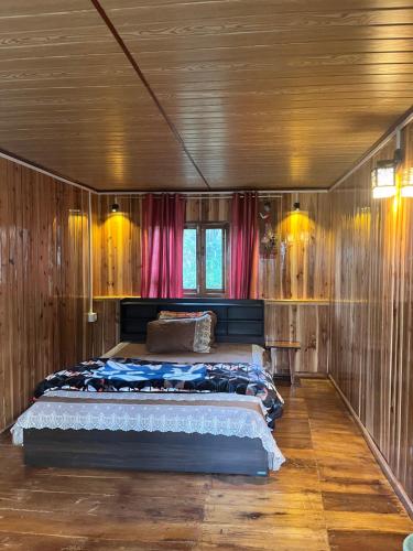 a bedroom with a bed in a room with wooden walls at Tamu Kyi Retreat in Kaluk