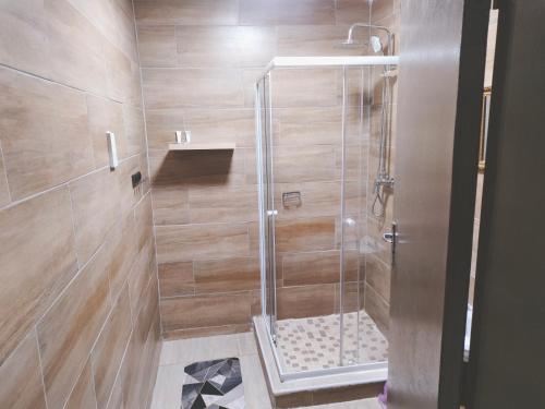 a shower with a glass door in a bathroom at Oloks Guest Inn in Francistown