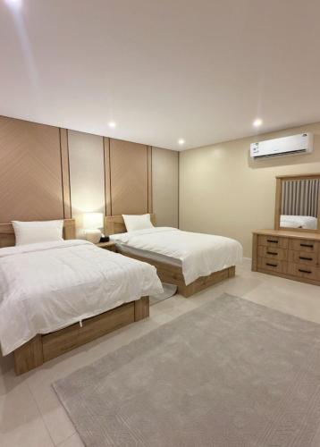 a bedroom with two beds and a tv on the wall at AINOSAH Residences in Medina