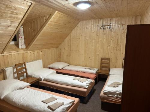 a room with four beds in a wooden room at Hotel Habsburg in České Hamry