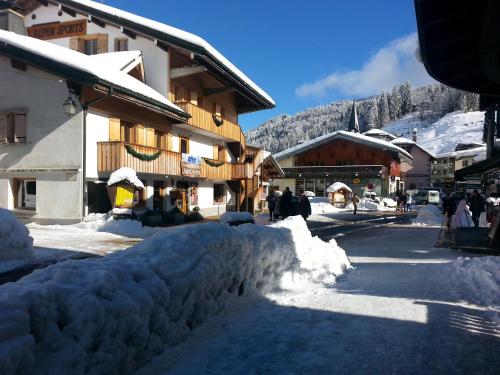 a street covered in snow next to a building at Loc'Hotel Alpen Sports in Les Gets