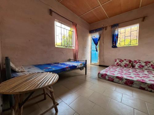 a room with a bed and a table and windows at Ibel dans le pays Bassaris in Kédougou