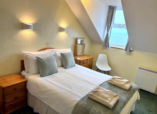a bedroom with a large white bed and a window at The Lookout in Ilfracombe