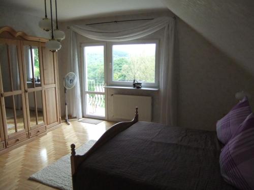 a bedroom with a bed and a large window at Villa Edelstein in Mörschied