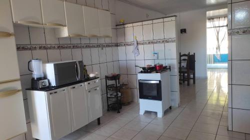 a kitchen with white cabinets and a stove top oven at Quarto em Casa Completa no Centro de Ilhéus in Ilhéus
