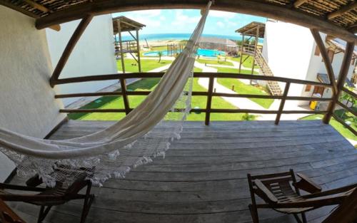 a hammock on a porch with a view of a beach at Hotel Vila Marola in Taíba