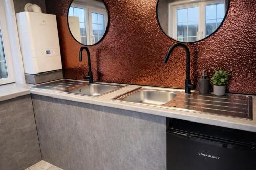 a kitchen with two sinks and two mirrors at Grass Roots Retreat in Llanstadwell