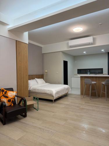 a bedroom with a bed and a couch and a kitchen at 簃居青衖 in Tainan
