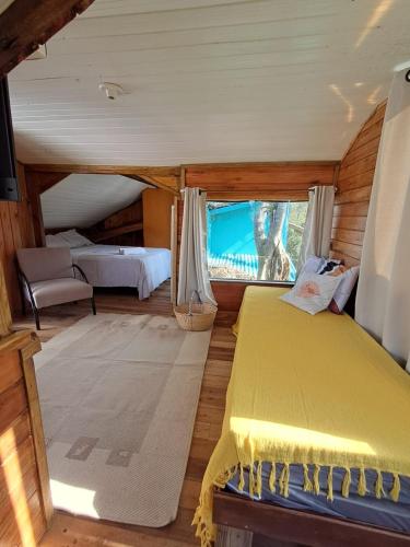 a bedroom with a yellow bed and a window at Treehouse albatroz hospedaria in Imbituba