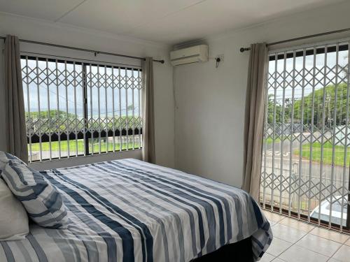 a bedroom with a bed and two large windows at Hawthorne By The Sea in Kingsborough