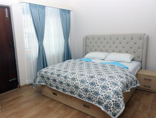 a bedroom with a bed with a blue and white comforter at New apartment in Hattigauda in Khadkagaon
