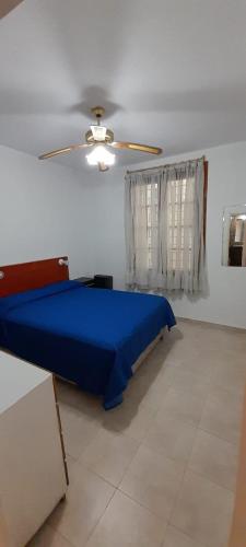 a bedroom with a blue bed and a ceiling fan at Casa 7 personas in Villa Gesell