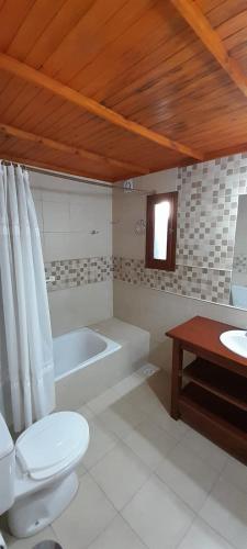 a bathroom with a toilet and a bath tub at Casa 7 personas in Villa Gesell
