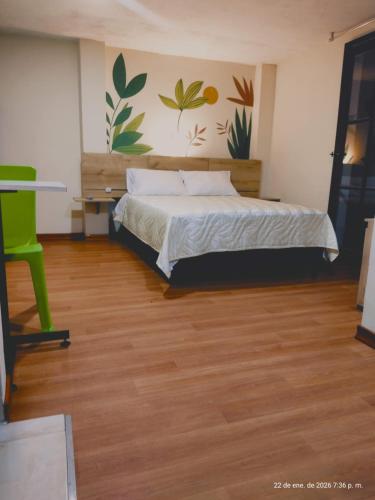a bedroom with a bed and a green chair at El Jardín cerca Aeropuerto de Pasto, comodidad y descanso in Chachagüí