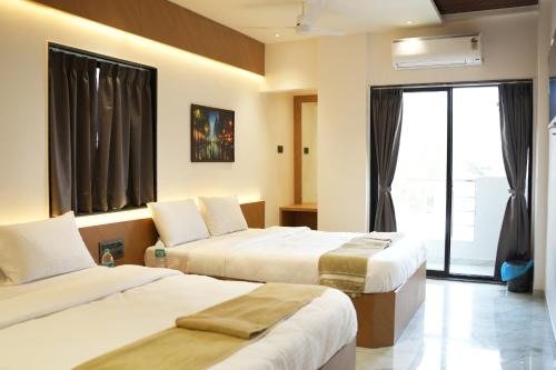 a hotel room with two beds and a window at Hotel Nature's Nest in Shirdi