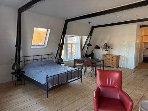 a bedroom with a bed and a chair and a table at Apartment in the city center near the Waterpoort in Sneek