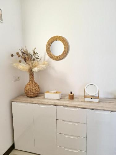 a counter with a mirror and a vase on it at Kopų tako apartamentai in Melnragė