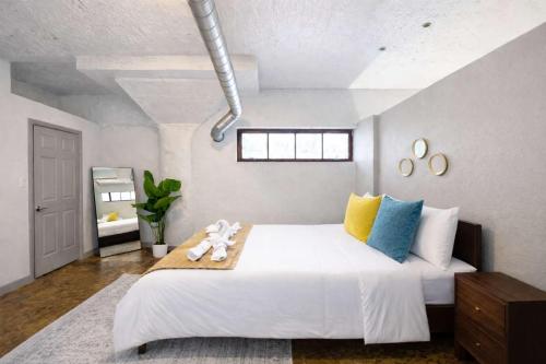 a bedroom with a large white bed with colorful pillows at 2BR River Market Loft for 6 - Rooftop & Gym in Kansas City