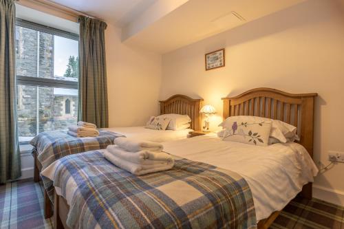 two twin beds in a room with a window at Torr Apartment Raven in Fort Augustus
