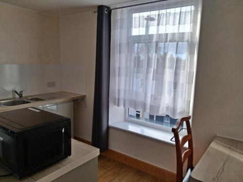 a kitchen with a window with a television and a sink at The Albert Hotel in Gloucester