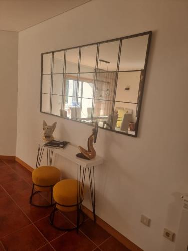 a mirror on a wall with two chairs and a table at Apartamento Familia Azevedo in Esposende