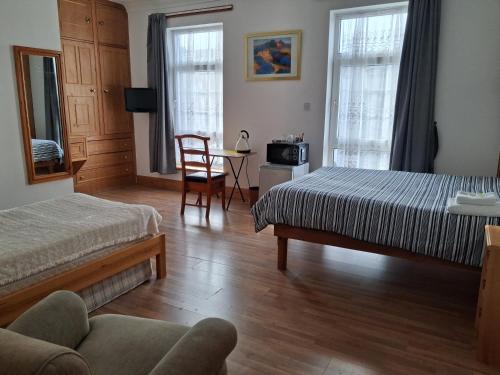 a bedroom with two beds and a table with a chair at The Albert Hotel in Gloucester