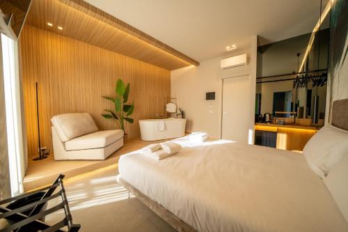 a bedroom with a white bed and a chair at Agorà Luxury Experience in Zafferana Etnea
