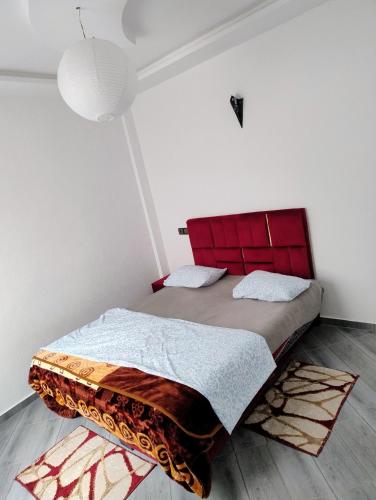 a bedroom with a large bed with a red headboard at tamraght samba 2 in Tamraght Ou Fella