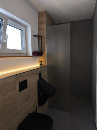 a bathroom with a black toilet and a window at Gästeunterkunft Bergzauber - Frühstück möglich in Scheibenberg