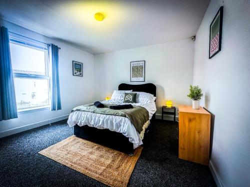 a bedroom with a bed and a table and a window at Worsley Gem, Modern 2BR with Garden Space in Worsley