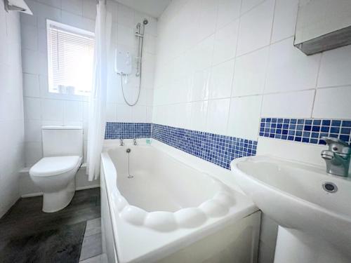 a bathroom with a tub and a toilet and a sink at Worsley Gem, Modern 2BR with Garden Space in Worsley