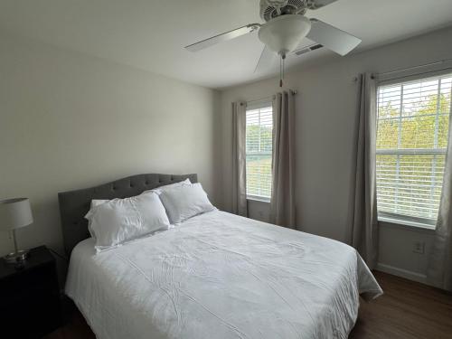 a bedroom with a white bed with a ceiling fan at Magnolia place in Cleveland
