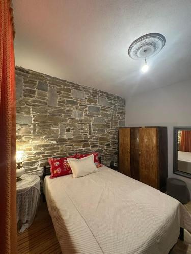 a bedroom with a bed and a stone wall at Thodis villa's in Karianí
