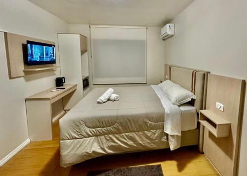 a small bedroom with a bed and a desk at Pousada Cores De Outono in Canela