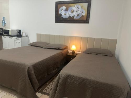 a bedroom with two beds and a lamp on a table at Kitnet no interior de São Paulo 22 in Serra Negra