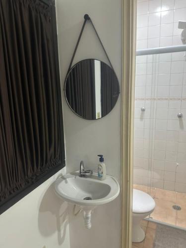 a bathroom with a sink and a mirror and a toilet at Kitnet no interior de São Paulo 22 in Serra Negra