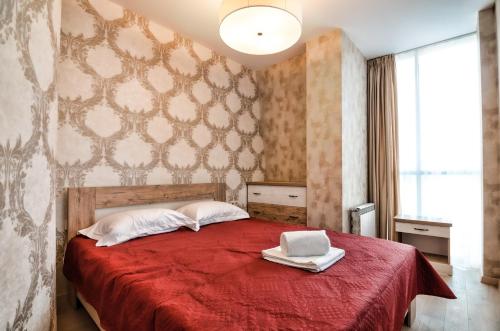 een slaapkamer met een rood bed en een laptop erop bij LEOGRAND Apartments z Panoramoyu Lvova in Lviv