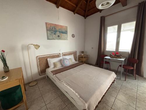 a bedroom with a bed and a table and window at MARIA 'S LITTLE HOUSE in Patitiri