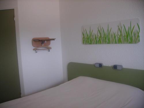 Un dormitorio con una cama y un cuadro de césped. en ibis budget Remiremont, en Remiremont