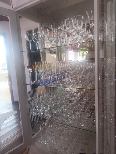 a bunch of wine glasses in a cabinet at Roame Hosting Boutique in Campos do Jordão