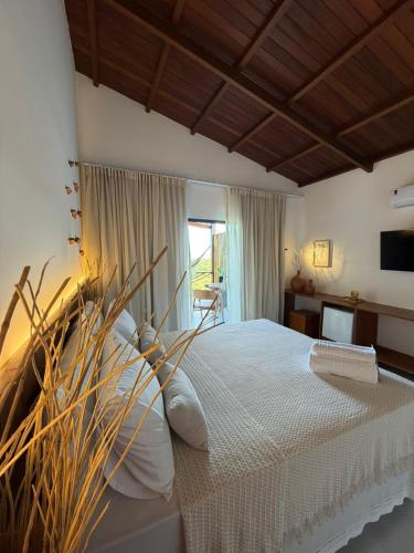 a bedroom with a bed with white sheets and a window at Pousada Almaré Boipeba in Ilha de Boipeba