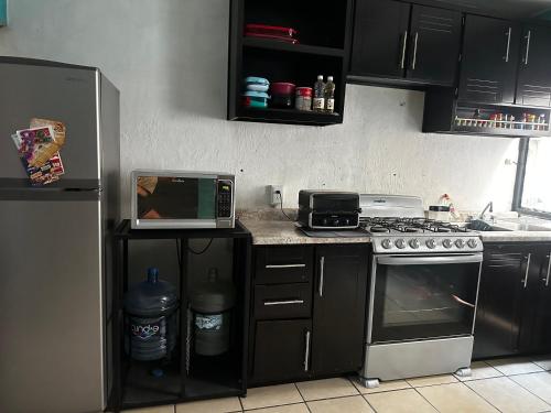 a kitchen with a stove and a microwave and a refrigerator at Cuarto a 4min del aeropuerto in Guadalajara