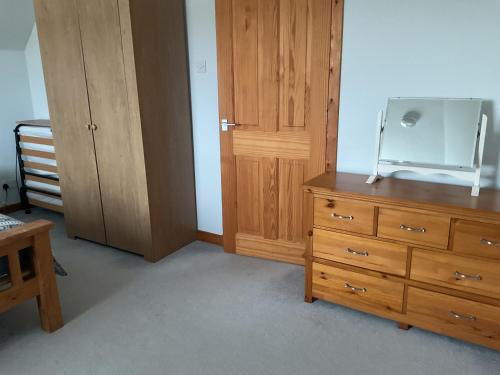 a bedroom with a wooden dresser with a mirror on it at Taighali Apartment in Aultbea